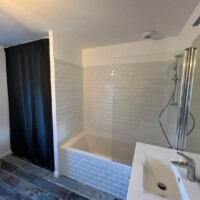Fully-tiled bathroom - bath, overhead shower and washbasin