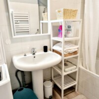 Bathroom with over-head shower, storage unit, wash basin and washing machine